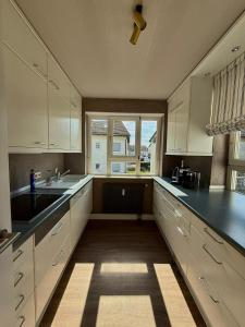 a kitchen with white cabinets and a large window at CASAMA am See in Langenargen +14 photos