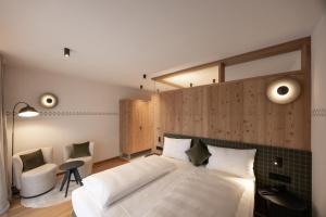 a bedroom with a large white bed and a chair at Hotel Ladinia in La Villa