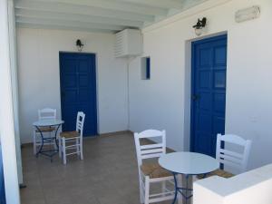 a room with two tables and chairs and blue doors at Amaranto Rooms in Aegiali