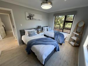 a bedroom with two beds and a window at Elephant View Homestead - Hydrangea Cottage in Plettenberg Bay