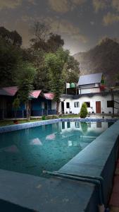 a swimming pool in front of a house at Hills Queen Resort And Camping in Mohan Chatti