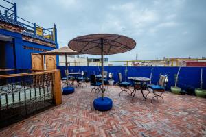a patio with tables and chairs and an umbrella at Riad Bleu Azahraa in Safi