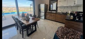a kitchen with a table with chairs and a refrigerator at Luxury Villa Rafaela Οικογενειακή βίλα με ιδιωτική πισίνα, BBQ κ παιχνίδια Ιδανική για οικογένειες με παιδια in Grevena