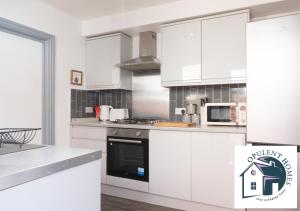 a kitchen with white cabinets and a stove top oven at Contactor Stay, Reading Town Centre 4 Bed House, Large House with 2 bath in Reading