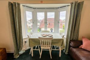 a dining room with a table and a large window at New Forest Flat Steps from Brockenhurst Station, Sleeps 4 in Brockenhurst +13 photos
