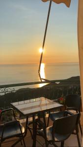a table and chairs on a balcony with the sunset at HORIZONT Rooms in Lukovë