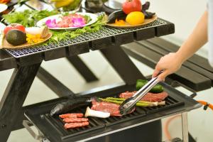 a person cooking meat and vegetables on a grill at TIDA house urasoe in Urazoe
