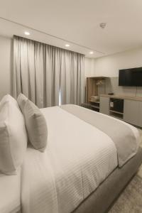 a bedroom with a large white bed and a television at Tibisay Hotel Boutique Morrocoy in Tucacas