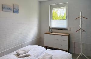a white bedroom with a bed and a window at Ferienhaus Wattglück Tossens in Butjadingen