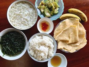 a table topped with bowls of food with rice and vegetables at Mama Pham Homestay in Tả Van