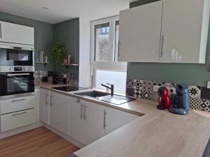 a kitchen with white cabinets and a sink at gîte 6 personnes le cocon des pommes in Saint-Lambert-et-Mont-de-Jeux