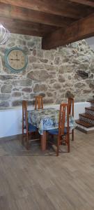 a table with two chairs and a clock on a wall at Casa Mitola in Congostro