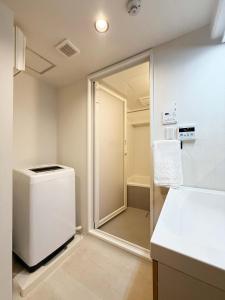 a small bathroom with a shower and a refrigerator at Origaminn 702 by b hotel - 5 mins PeacePark in Hiroshima