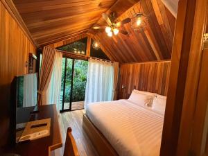 a bedroom with a bed with a ceiling fan and a window at Lush inn Phuket in Ban Suan
