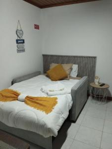 a bedroom with a large bed with white sheets and brown pillows at Casa de Lá in São Roque do Pico