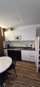a kitchen with white cabinets and a table and a microwave at Enebrales Home in Punta Umbría
