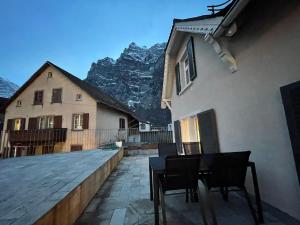 a patio with chairs and a house and mountains at vitalpha lodge - house in Glarus