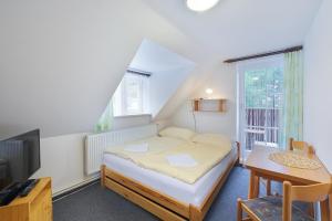 a small bedroom with a bed and a table at Pension Katty in Špindlerův Mlýn