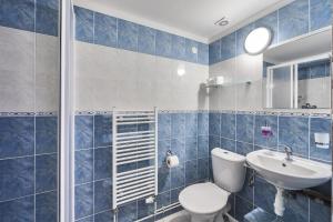 a blue tiled bathroom with a toilet and a sink at Pension Katty in Špindlerův Mlýn +38 photos