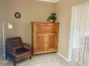 a chair and a wooden cabinet in a room at OM East in Aizpute +2 photos