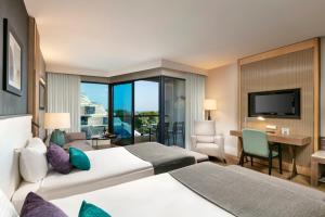 a hotel room with two beds and a television at Susesi Luxury Resort in Belek