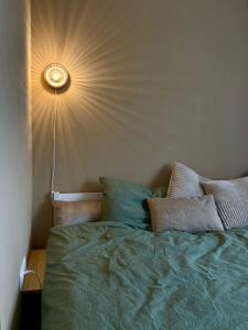 a bedroom with a green bed with a light on the wall at OM East in Aizpute