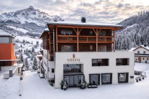 a large building in the snow in front of a mountain at Soleil Alpine Lifestyle Hotel in La Villa