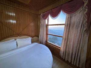 a bedroom with a large bed and a window at New Amar Palace Shimla with Mountain View in Shimla