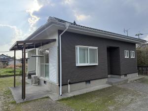 a small black house with a white window at 宿Oshikiri 04 in Shibushi