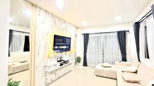 a living room with a couch and a tv at Baan Thanaluk 1 Pattaya in Pattaya
