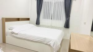 a bedroom with a white bed and a window at Baan Thanaluk 1 Pattaya in Pattaya