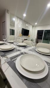 a table with white plates and wine glasses on it at Baan Thanaluk 1 Pattaya in Pattaya