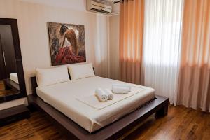 a bedroom with a bed with a painting on the wall at Central Blloku 2 bedroom Apartment in Tirana