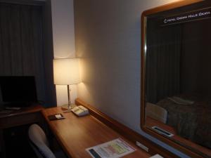 a room with a desk with a lamp and a mirror at Hotel Crown Hills Okaya in Okaya