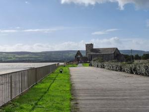 a walkway leading to an old building next to a body of water at Tom's Alpaca Cottage in Mooncoin