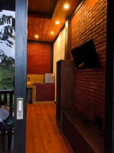a living room with a brick wall and a tv at Tetebatu Valley Bungalows in Tetebatu
