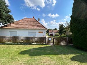 a white house with a wooden fence in a yard at Jäger-Lodge in Lócs