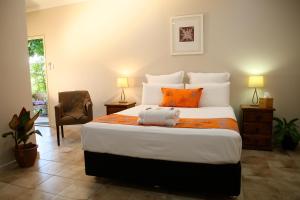 una camera da letto con un grande letto con cuscini arancioni di Wunan House a Kununurra