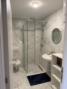 a white bathroom with a shower and a sink at Tiffany apartment - Podgorica in Podgorica +14 photos
