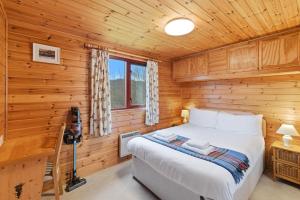 a bedroom with a bed in a wooden cabin at Braeknowe Scottish Cabin Getaway in Dunkeld