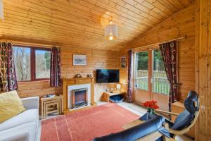 a living room with a fireplace and a tv at Braeknowe Scottish Cabin Getaway in Dunkeld