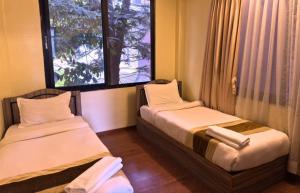 two beds in a room with a window at Yangchen Home Hotel in Kathmandu