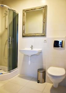 een badkamer met een wastafel, een toilet en een spiegel bij Karczma We Młynie in Tuszyn