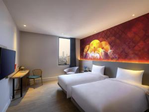a hotel room with two beds and a tv at ibis Styles Bangkok Ratchada in Bangkok
