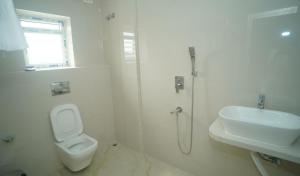 a white bathroom with a toilet and a sink at Siddharaj Resort in Mal bazar
