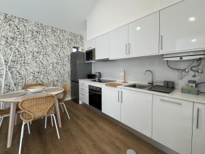 a kitchen with white cabinets and a table and chairs at Stayin Arrifes I C in Funchal