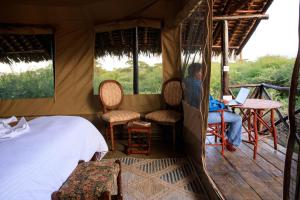 a person in a tent with a bed and a laptop at Olemayian Amboseli Cottages in Amboseli