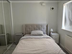a bed in a white room with a mirror at Luxury 2-Bed Apartment with Parking & Garden in Borehamwood