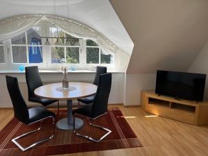 a dining room with a table and chairs and a television at Ferienhaus Mine Sehnsucht in Dierhagen