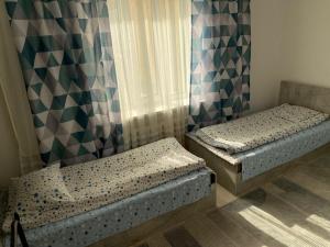 two twin beds in a room with a window at Жумгал гостевой дом in Chayek
